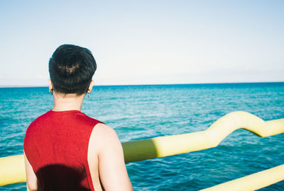 Rear view of man looking at sea against sky