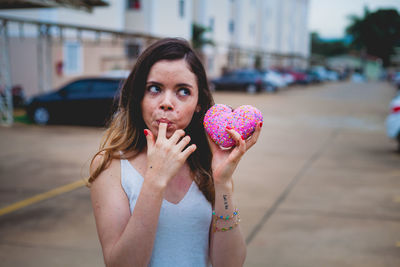 Beautiful woman holding candy while standing on footpath