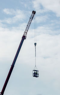 Low angle view of crane against cloudy sky