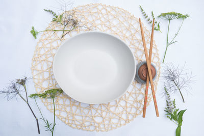 Directly above shot of empty bowl with chopsticks with leaves arranged on table