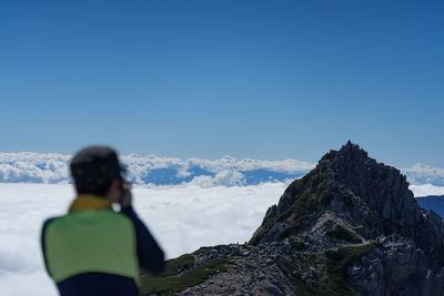 Rear view of person on snowcapped mountain against clear sky