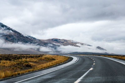 Road leading towards mountains against sky