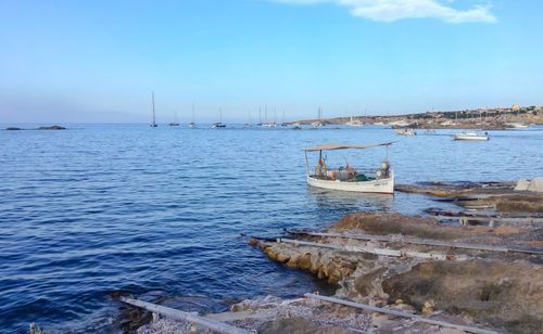 Sailboats moored on sea against sky