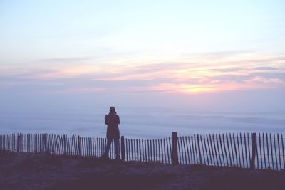 Man standing on beach against sky during sunset