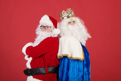 Portrait of woman wearing santa hat standing against yellow background