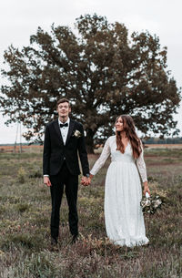 Newlywed couple standing on grassy land