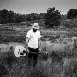 Boy on grassy field against trees
