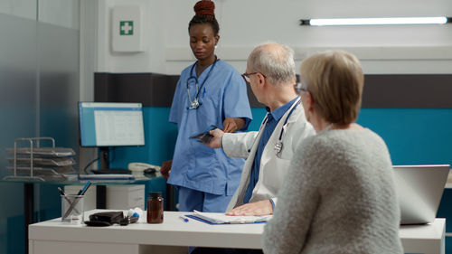 Doctor talking with nurse sitting in front of patient at clinic