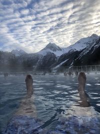 People on snowcapped mountain by lake against sky