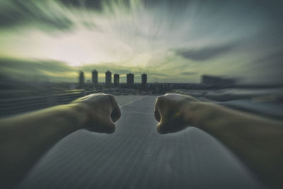 Close-up of hands against sky