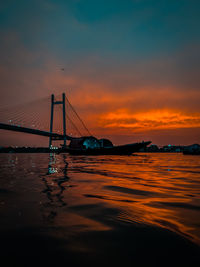 Bridge over sea against sky during sunset