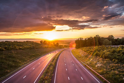 High angle view of two lane highway amidst landscape at sunset