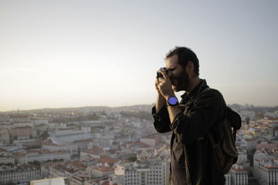 Man photographing cityscape against clear sky