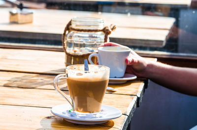 Cropped image of person holding coffee cup at table