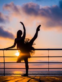 Silhouette ballet dancer dancing against sea during sunset