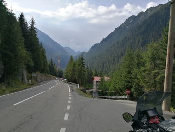 Road by mountains against sky