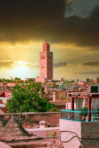 Tower amidst buildings against sky during sunset