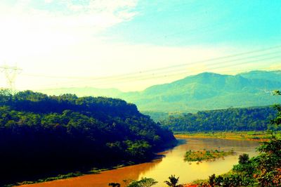 Scenic view of river by mountains against sky