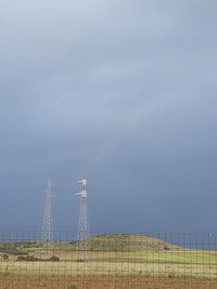 Electricity pylon on field against sky