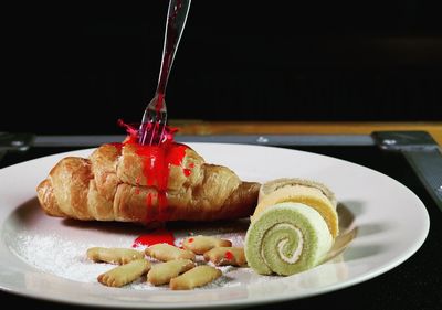 Close-up of fork on croissant in plate 