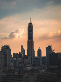 Modern buildings in city against sky during sunset