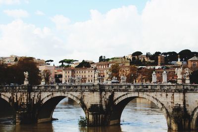 Bridge over river in city against sky