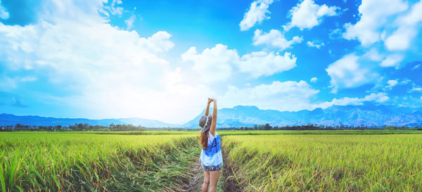 Rear view of woman standing on field against sky