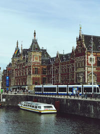 Buildings by river against sky in city