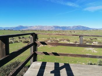 Scenic view of field and mountains against blue sky