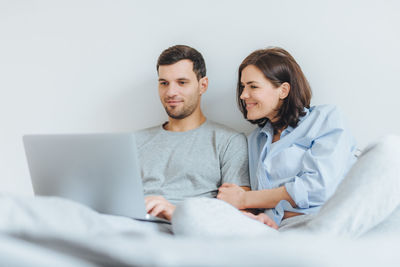 Low angle view of couple watching video over laptop on bed at home