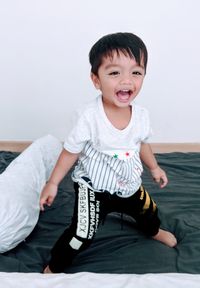 Portrait of cheerful boy standing on bed