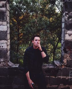 Portrait of young man standing against wall