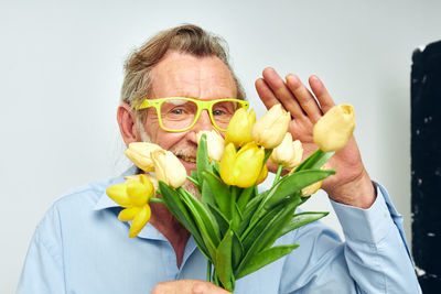 Portrait of young woman holding flower against white background