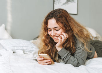 Smiling young woman lying on bed