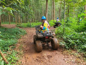 Man cycling on road amidst trees in forest