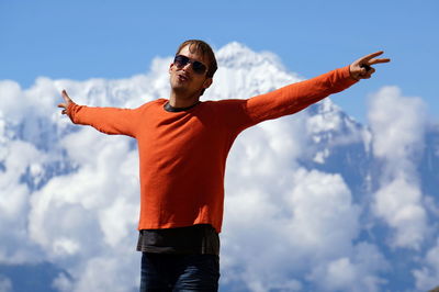 Young man is standing, spread his arms wide, against annapurna massif.  upper mustang. nepal.