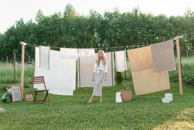 Laundry day. a woman hangs linen and towels on a tree in the courtyard of a village house.