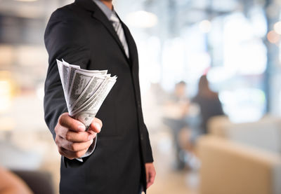 Midsection of businessman holding paper currencies at office