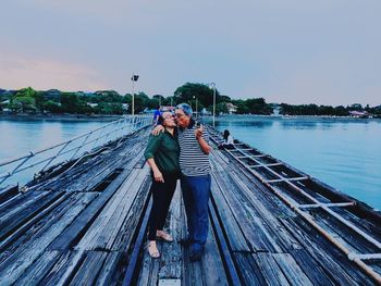 Full length of mature couple kissing while standing on footbridge