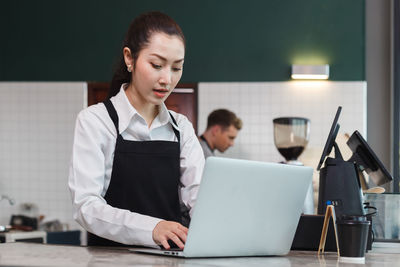 Businesswoman using laptop while sitting on table