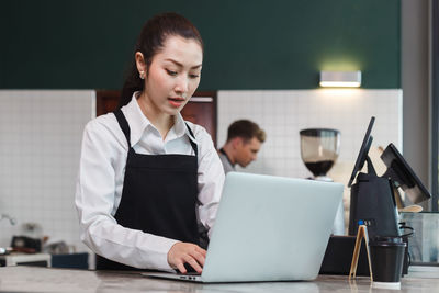 Barista using laptop at restaurant