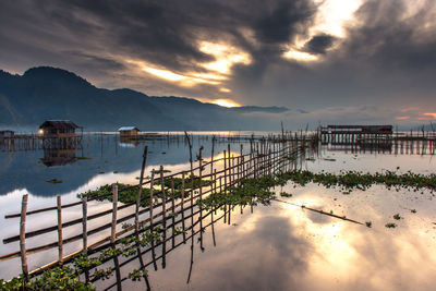 Pier on lake against sky during sunset