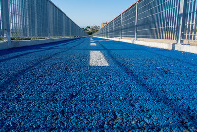 Surface level of road against blue sky in city