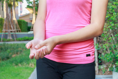 Midsection of woman rubbing palm while standing outdoors