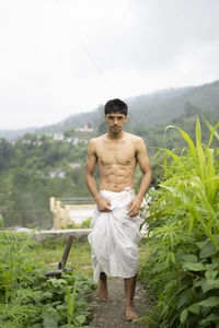 Young indian fit boy, walking on a pathway beside crops in the field. an indian priest walking.