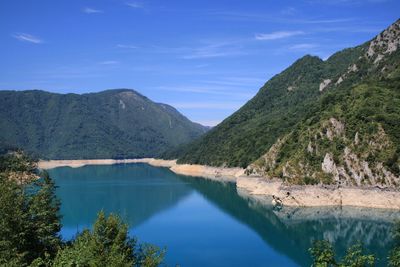 Scenic view of lake and mountains against blue sky