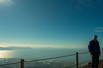 Young man standing on observation point against blue sky during sunset