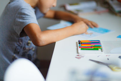 Midsection of boy drawing on paper