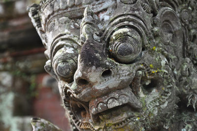 Close-up of weathered guardian statue at temple