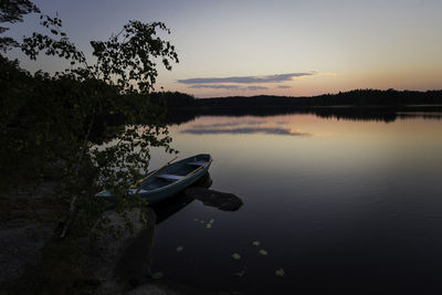 Boat moored in lake against sky during sunset
